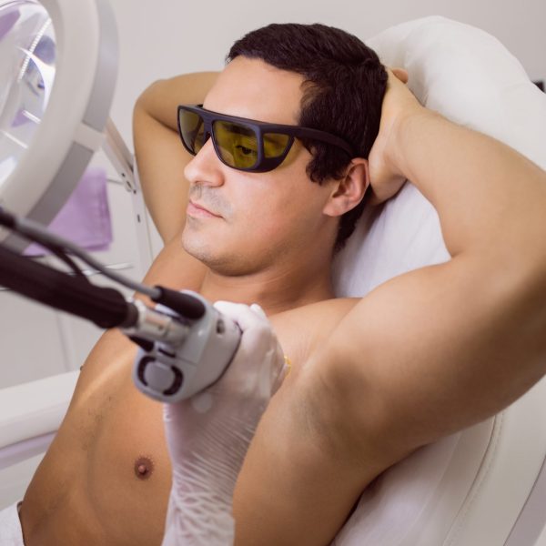 Doctor performing laser hair removal on male patient skin in clinic